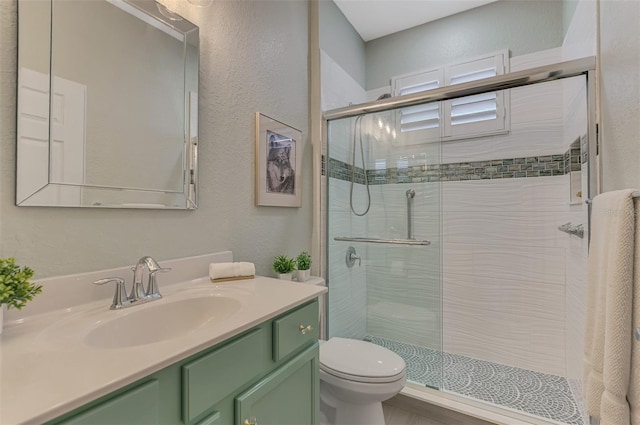 full bathroom with toilet, a textured wall, a shower stall, and vanity