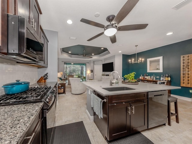 kitchen featuring pendant lighting, sink, an island with sink, dark brown cabinets, and stainless steel appliances