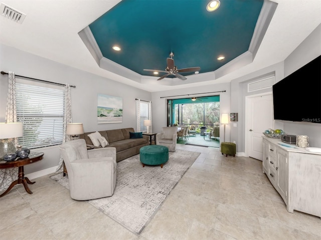 living room featuring a tray ceiling and ceiling fan