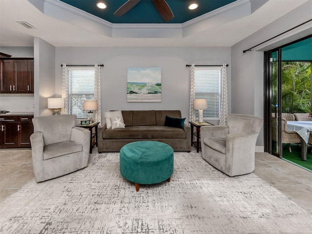 living room featuring a tray ceiling, ceiling fan, and ornamental molding