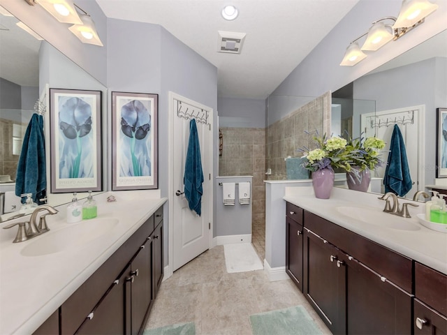 bathroom featuring a tile shower and vanity