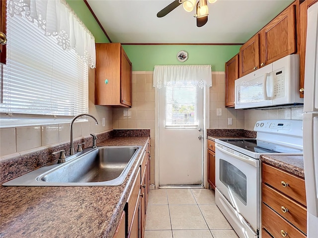 kitchen featuring white appliances, sink, ceiling fan, light tile patterned floors, and tasteful backsplash