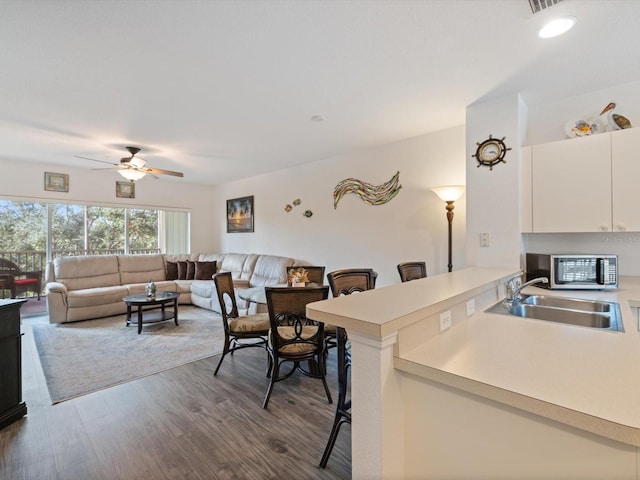 kitchen featuring white cabinetry, sink, ceiling fan, hardwood / wood-style floors, and a kitchen bar