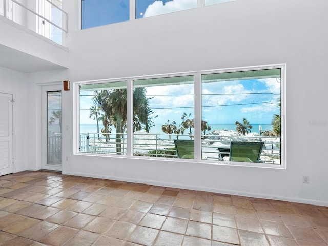 unfurnished room with a water view, a towering ceiling, and a wealth of natural light