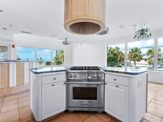 kitchen featuring high end stove, white cabinetry, a kitchen island, and light tile patterned flooring