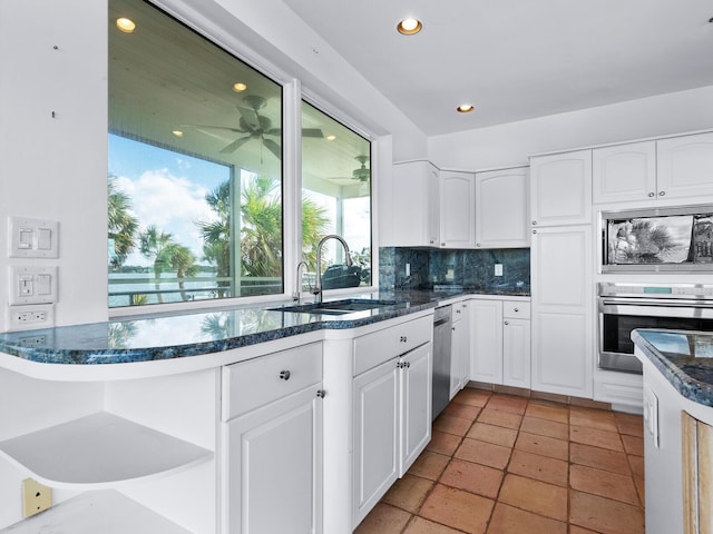 kitchen featuring white cabinetry, sink, stainless steel appliances, tasteful backsplash, and light tile patterned floors