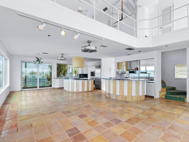 kitchen with stainless steel built in fridge, white cabinets, a high ceiling, a kitchen island, and light tile patterned flooring