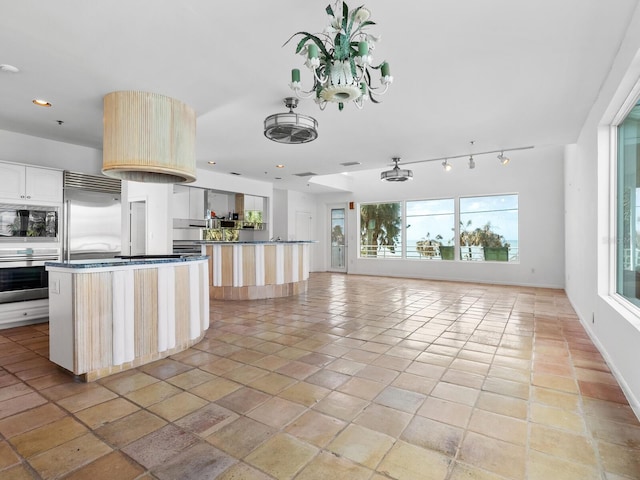 kitchen with built in appliances, a kitchen island, and a notable chandelier