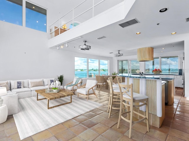 kitchen featuring a kitchen breakfast bar, a water view, ceiling fan, light tile patterned floors, and a kitchen island