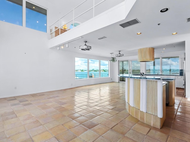 kitchen with a center island, sink, stone countertops, a breakfast bar, and light tile patterned floors