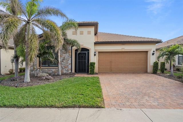 13807 Karina St, Venice, FL 34293 - mediterranean / spanish-style house featuring an attached garage, decorative driveway, a tiled roof, stucco siding, and a front yard