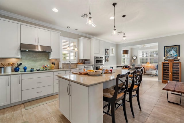 kitchen featuring appliances with stainless steel finishes, ceiling fan, pendant lighting, white cabinets, and a center island