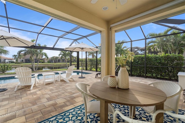 view of patio with a water view, glass enclosure, and ceiling fan