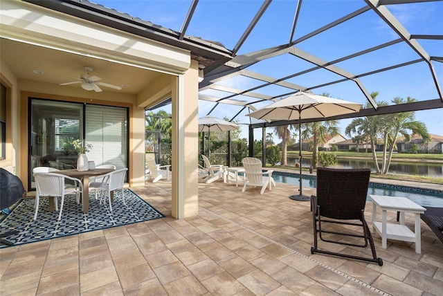 view of patio / terrace featuring ceiling fan, a water view, and glass enclosure