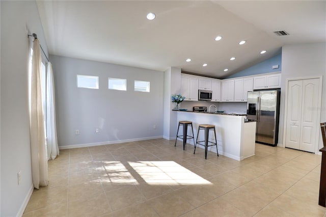 kitchen with a breakfast bar, white cabinets, light tile patterned floors, appliances with stainless steel finishes, and kitchen peninsula