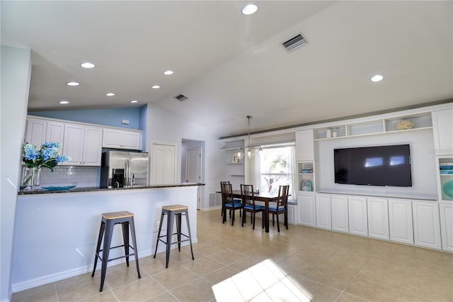 kitchen with white cabinetry, stainless steel refrigerator with ice dispenser, backsplash, vaulted ceiling, and decorative light fixtures