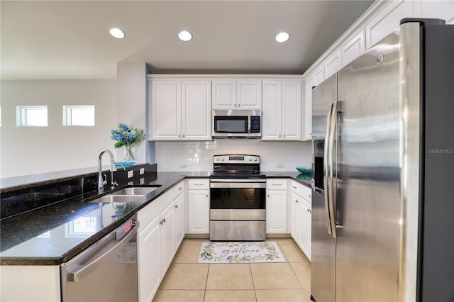 kitchen with white cabinets, sink, dark stone countertops, appliances with stainless steel finishes, and kitchen peninsula