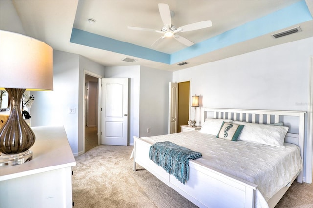 bedroom featuring ceiling fan, a raised ceiling, and light carpet