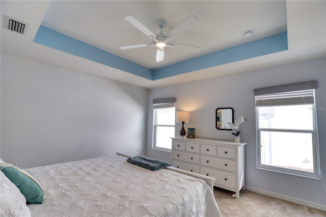 carpeted bedroom featuring ceiling fan and a tray ceiling