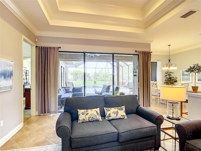 living room featuring a chandelier, light tile patterned floors, a tray ceiling, and crown molding