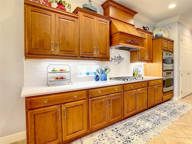 kitchen with backsplash, custom exhaust hood, stainless steel appliances, crown molding, and light tile patterned floors