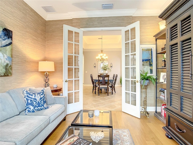 living room with a chandelier, crown molding, and french doors