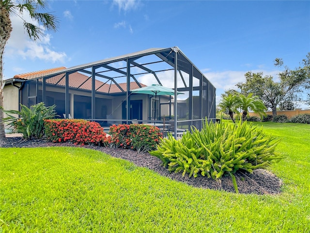 rear view of house with a lanai and a lawn