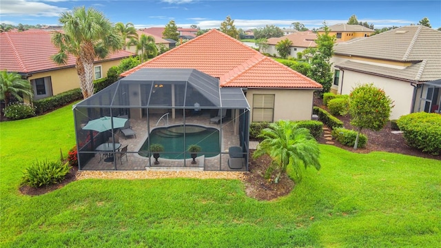 back of house with a yard, glass enclosure, and a patio area