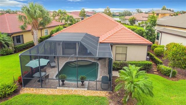 rear view of property with a lawn, glass enclosure, and a patio