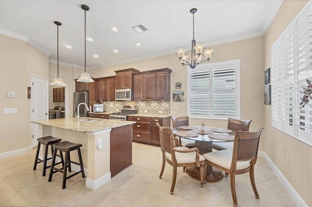 kitchen with sink, hanging light fixtures, an island with sink, a notable chandelier, and stainless steel appliances