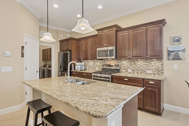 kitchen featuring appliances with stainless steel finishes, backsplash, sink, a center island with sink, and independent washer and dryer