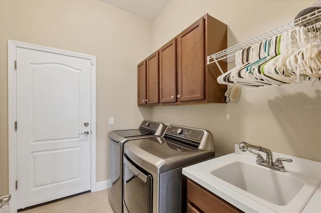 clothes washing area featuring light tile patterned flooring, cabinets, separate washer and dryer, and sink