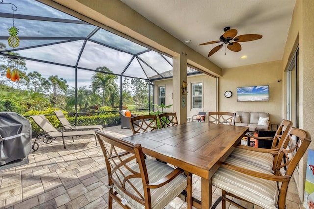 view of patio featuring area for grilling, ceiling fan, and glass enclosure