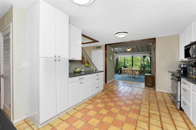 kitchen with ceiling fan, white cabinets, light tile patterned flooring, and stainless steel range oven