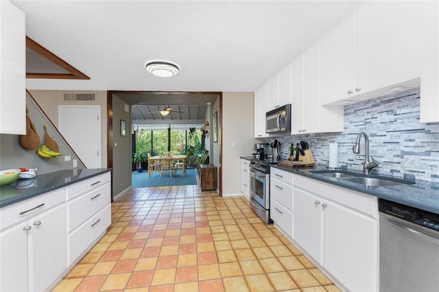 kitchen featuring appliances with stainless steel finishes, backsplash, sink, white cabinets, and light tile patterned flooring