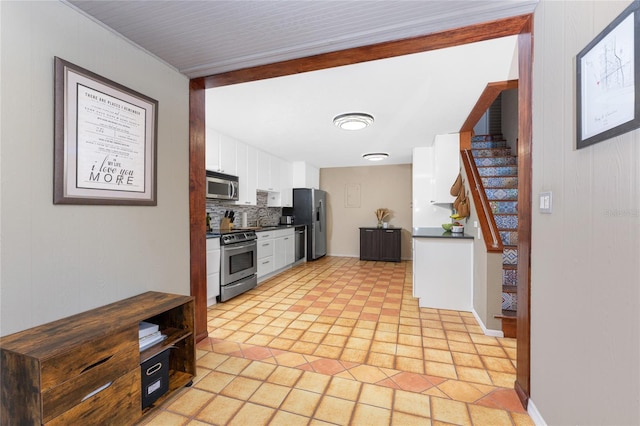 kitchen featuring sink, stainless steel appliances, light tile patterned floors, tasteful backsplash, and white cabinets