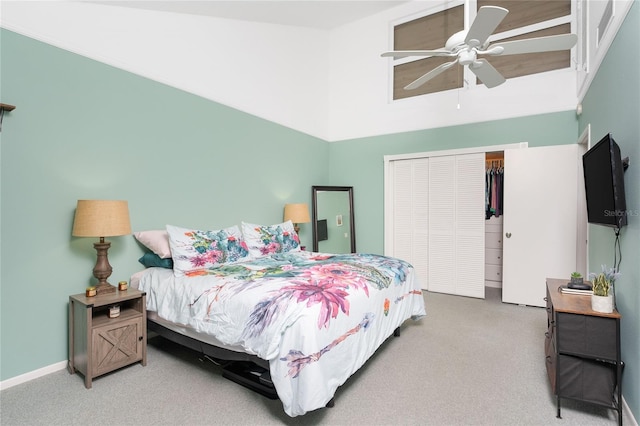 carpeted bedroom with ceiling fan, a closet, and a high ceiling