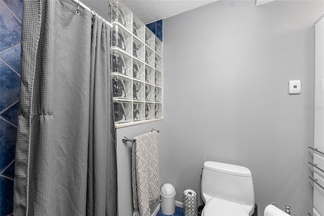 bathroom featuring a shower with shower curtain and toilet