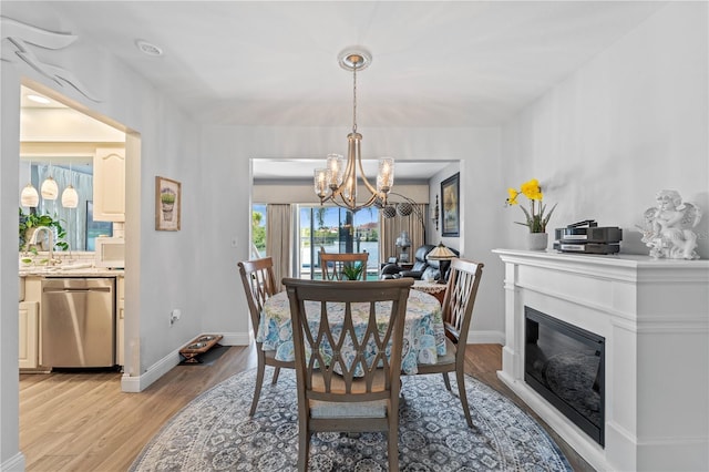 dining area with an inviting chandelier, sink, and light hardwood / wood-style floors