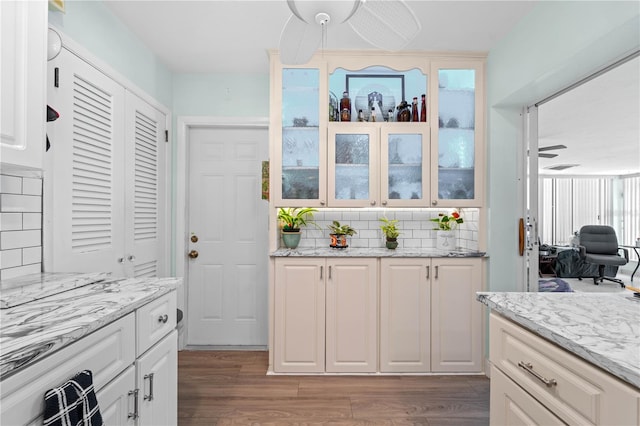 kitchen with light stone counters, backsplash, dark hardwood / wood-style floors, and ceiling fan