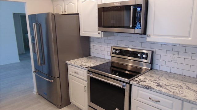 922 Casey Cove Dr, Nokomis, FL 34275 - kitchen with decorative backsplash, white cabinets, stainless steel appliances, and light wood-style floors