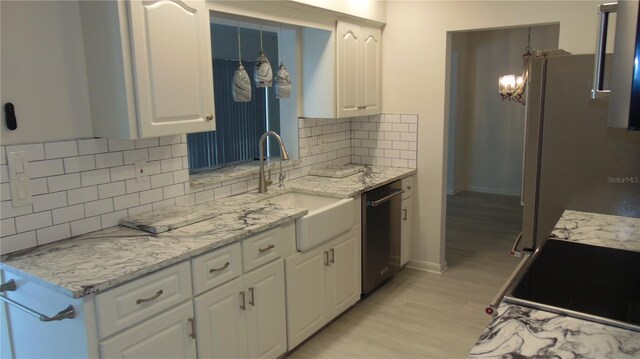 922 Casey Cove Dr, Nokomis, FL 34275 - kitchen with light wood-type flooring, a sink, stainless steel dishwasher, backsplash, and white cabinetry