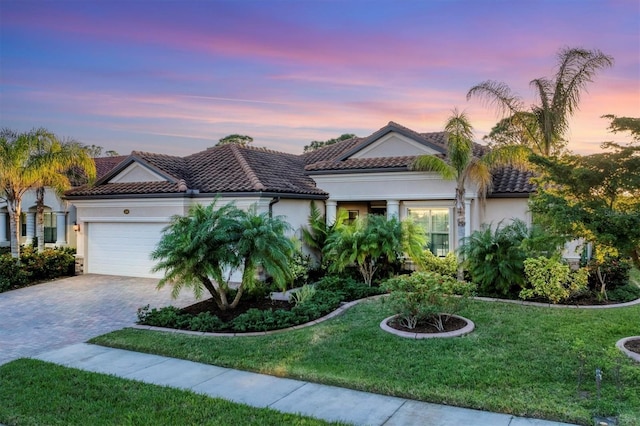 mediterranean / spanish-style home featuring a lawn and a garage