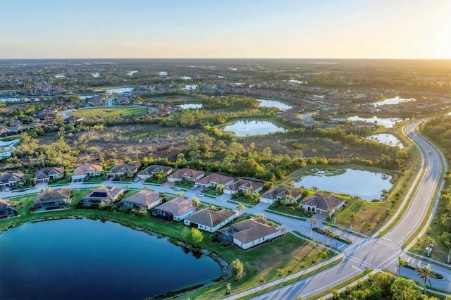 aerial view at dusk featuring a water view