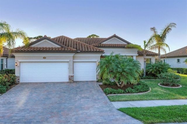 mediterranean / spanish house with a garage and a front lawn