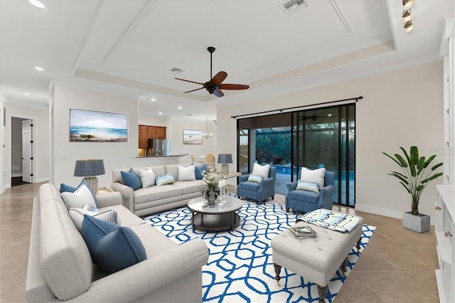 tiled living room featuring a tray ceiling, ceiling fan, and ornamental molding