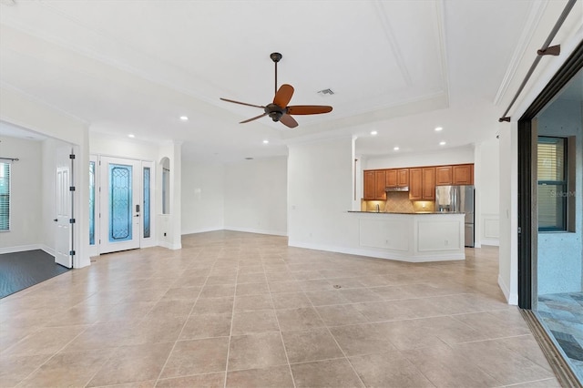 unfurnished living room with ceiling fan, light tile patterned flooring, a raised ceiling, and ornamental molding