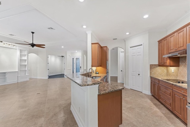 kitchen featuring sink, kitchen peninsula, crown molding, dark stone counters, and black electric cooktop