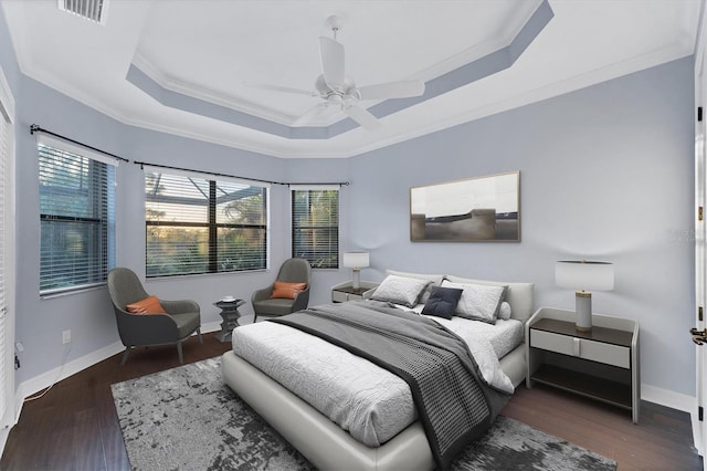 bedroom with a raised ceiling, multiple windows, ceiling fan, and ornamental molding