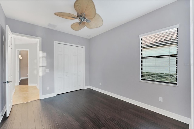 unfurnished bedroom featuring dark hardwood / wood-style flooring, a closet, and ceiling fan